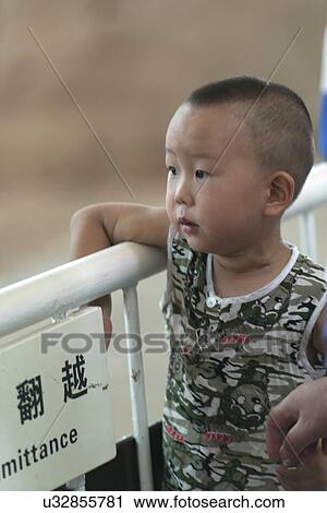 Stock Image - Little boy looking with curiosity at Terracotta Warriors Army Museum, Xi'an, Shaanxi, China. Fotosearch