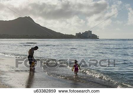 Stock Photo - Man with his children on the beach, Waikiki, Honolulu, Oahu, Hawaii, USA. Fotosearch