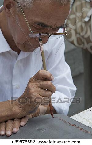 Stock Image - Old man writing chinese calligraphy, Xi'an, Shaanxi, China.. Fotosearch