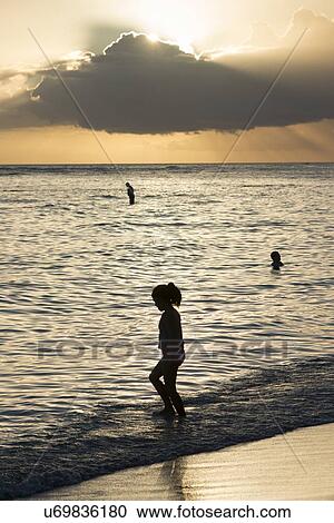 Stock Image - People enjoying the beach at sunset, Waikiki, Honolulu, Oahu, Hawaii, USA. Fotosearch