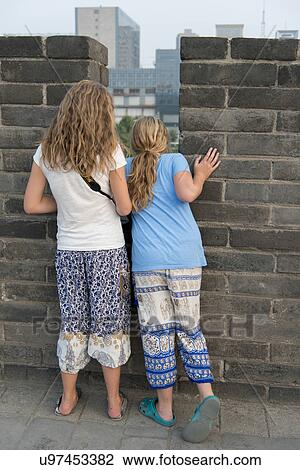 Rear view of teenage girls looking down from Xian City Wall, Xi'an, Shaanxi, China. View Large Photo Image Stock Image - Rear view of teenage girls looking down from Xian City Wall, Xi'an, Shaanxi, China.. Fotosearch