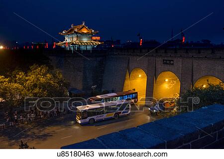Stock Image - Road traffic, illuminated building in distant at Lianhu Ancient City Wall, Xi'an, Shaanxi, China.. Fotosearch