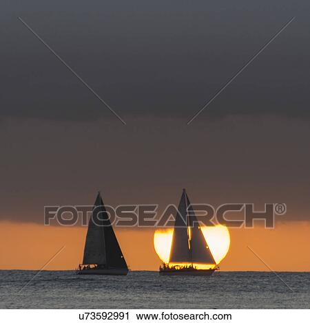 Stock Image - Sailboats in the ocean at sunset, Waikiki, Honolulu, Oahu, Hawaii, USA. Fotosearch