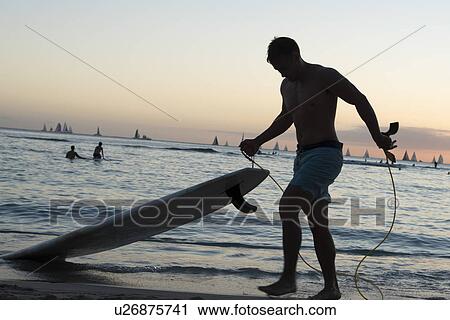 Surfer on the beach at dusk, Waikiki, Honolulu, Oahu, Hawaii, USA View Large Photo Image Stock Image - Surfer on the beach at dusk, Waikiki, Honolulu, Oahu, Hawaii, USA. Fotosearch