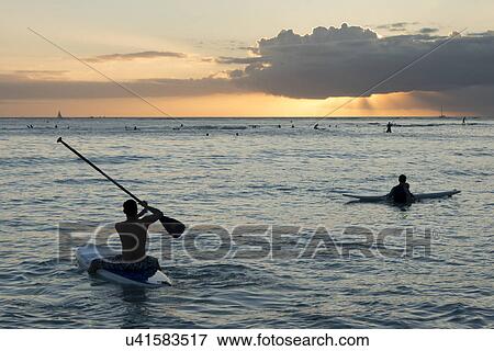 Stock Photo - Surfers and boaters in the ocean at sunset, Waikiki, Honolulu, Oahu, Hawaii, USA. Fotosearch