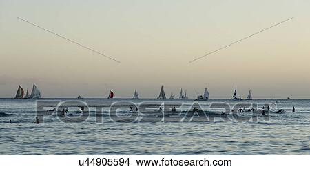 Picture - Surfers and sailboats in the ocean at sunset, Waikiki, Honolulu, Oahu, Hawaii, USA. Fotosearch