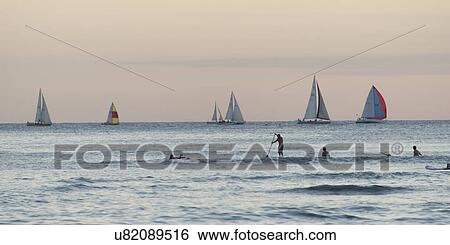 Surfers with sailboats in the background, Waikiki, Honolulu, Oahu, Hawaii, USA View Large Photo Image Stock Photograph - Surfers with sailboats in the background, Waikiki, Honolulu, Oahu, Hawaii, USA. Fotosearch