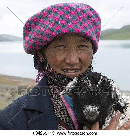 Stock Photo - Woman holding a lamb at the lakeside, Yamdrok Lake, Tibet, China. Fotosearch