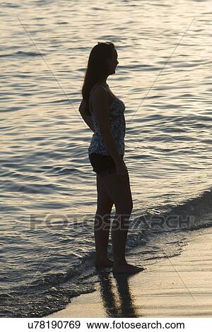 Stock Photo - Woman standing on the beach at sunset, Waikiki, Honolulu, Oahu, Hawaii, USA. Fotosearch