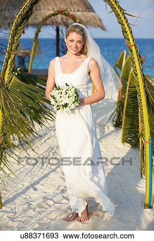 Stock Image - Beautiful Bride Getting Married In Beach Ceremony. Fotosearch