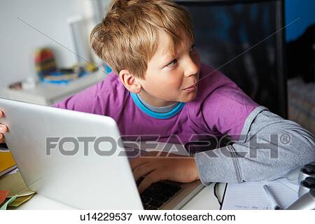 Stock Photo - Boy Behaving Suspiciously Whilst Using Laptop. Fotosearch