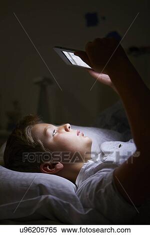 Stock Photography - Boy Looking At Digital Tablet In Bed At Night. Fotosearch
