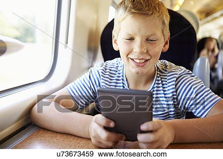 Stock Photo - Boy Reading E Book On Train Journey. Fotosearch