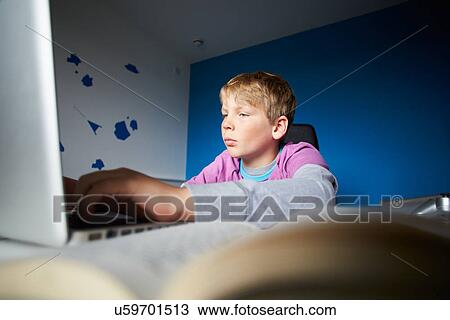 Stock Image - Boy Studying In Bedroom Using Laptop. Fotosearch
