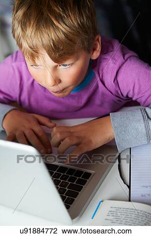Stock Image - Boy Studying In Bedroom Using Laptop. Fotosearch
