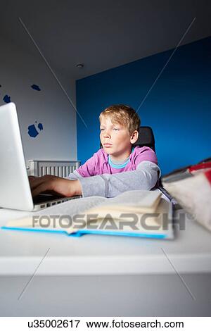 Stock Photo - Boy Studying In Bedroom Using Laptop. Fotosearch