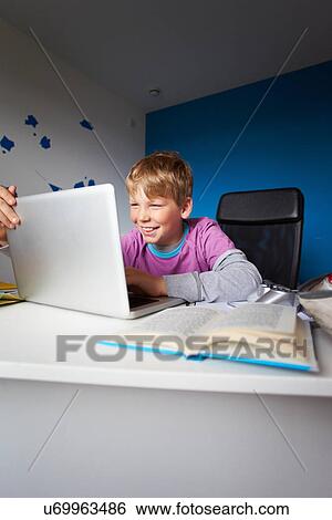 Stock Photograph - Boy Studying In Bedroom Using Laptop. Fotosearch