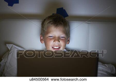 Picture - Boy Using Laptop In Bed At Night. Fotosearch