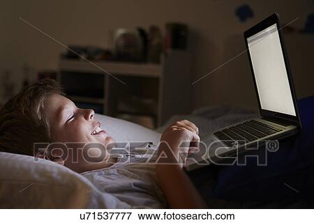 Boy Using Laptop In Bed At Night View Large Photo Image Stock Photo - Boy Using Laptop In Bed At Night. Fotosearch