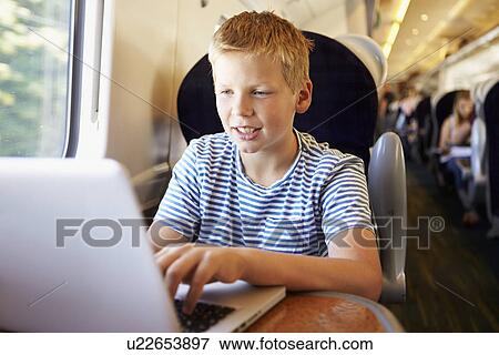 Boy Using Laptop On Train Journey View Large Photo Image Stock Photo - Boy Using Laptop On Train Journey. Fotosearch
