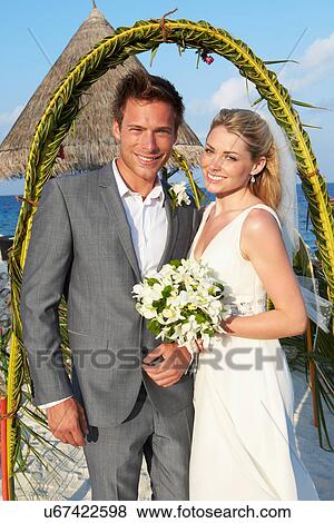 Stock Photo - Bride And Groom Getting Married In Beach Ceremony. Fotosearch