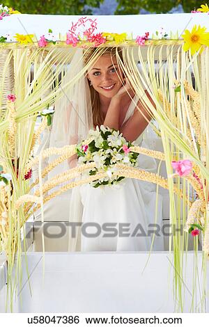 Stock Photograph - Bride Sitting Under Decorated Canopy At Wedding. Fotosearch
