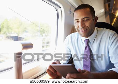 Businessman Commuting On Train Reading E Book View Large Photo Image Stock Photo - Businessman Commuting On Train Reading E Book. Fotosearch