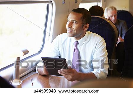 Businessman Commuting On Train Using Digital Tablet View Large Photo Image Stock Image - Businessman Commuting On Train Using Digital Tablet. Fotosearch