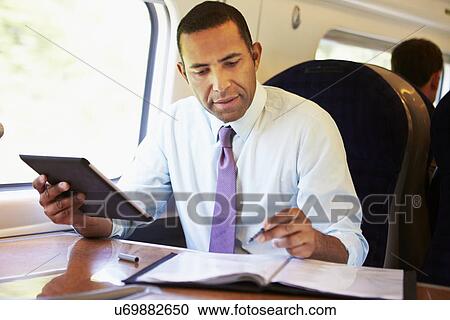Businessman Commuting On Train Using Digital Tablet View Large Photo Image Stock Image - Businessman Commuting On Train Using Digital Tablet. Fotosearch