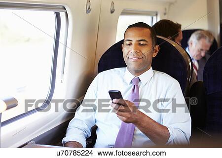 Businessman Commuting To Work On Train Using Mobile Phone View Large Photo Image Picture - Businessman Commuting To Work On Train Using Mobile Phone. Fotosearch