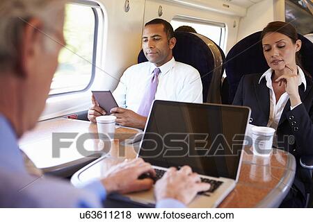 Stock Photo - Businessman Commuting To Work On Train And Using Laptop. Fotosearch