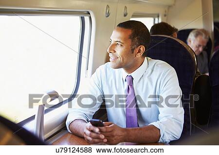 Businessman Commuting To Work On Train Using Mobile Phone View Large Photo Image Stock Photo - Businessman Commuting To Work On Train Using Mobile Phone. Fotosearch