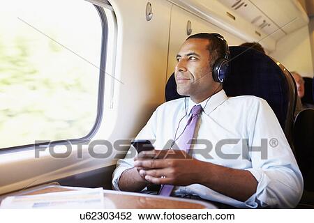 Businessman Relaxing On Train Listening To Music View Large Photo Image Stock Image - Businessman Relaxing On Train Listening To Music. Fotosearch