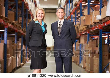 Stock Image - Businesswoman And Businessman In Distribution Warehouse. Fotosearch
