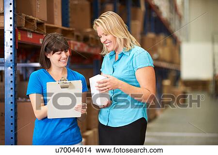 Businesswoman And Female Worker In Distribution Warehouse View Large Photo Image Picture - Businesswoman And Female Worker In Distribution Warehouse. Fotosearch