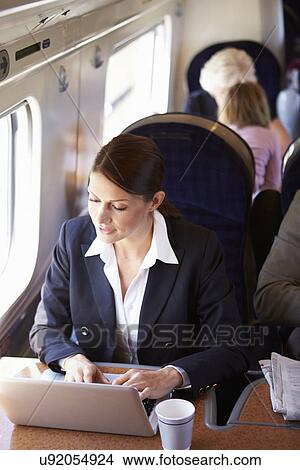 Picture - Businesswoman Commuting To Work On Train And Using Laptop. Fotosearch