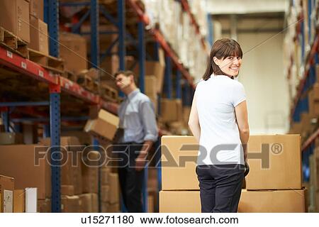 Stock Image - Businesswoman Pulling Pallet In Warehouse. Fotosearch