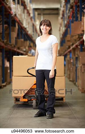 Stock Image - Businesswoman Pulling Pallet In Warehouse. Fotosearch