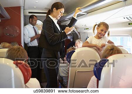 Stock Image - Businesswoman Using Mobile Phone On Busy Commuter Train. Fotosearch