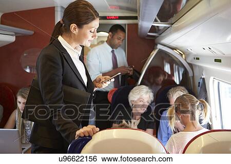 Stock Photograph - Businesswoman Using Mobile Phone On Busy Commuter Train. Fotosearch