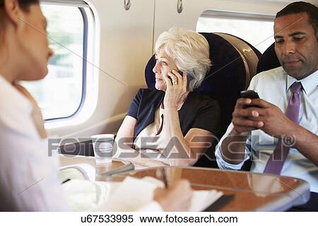 Stock Photography - Businesswoman Using Mobile Phone On Busy Commuter Train. Fotosearch
