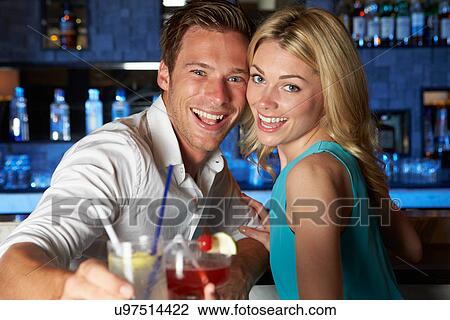 Stock Image - Couple Enjoying Cocktail In Bar. Fotosearch
