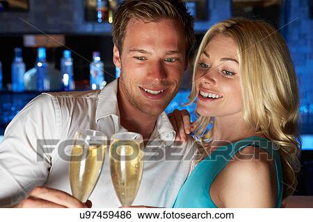 Stock Photograph - Couple Enjoying Glass Of Champagne In Bar. Fotosearch