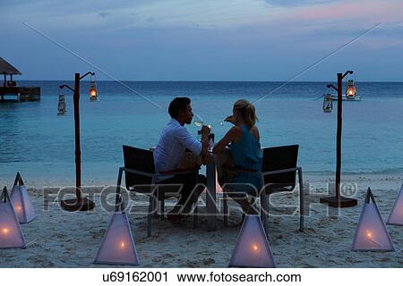 Stock Image - Couple Enjoying Late Meal In Outdoor Restaurant. Fotosearch
