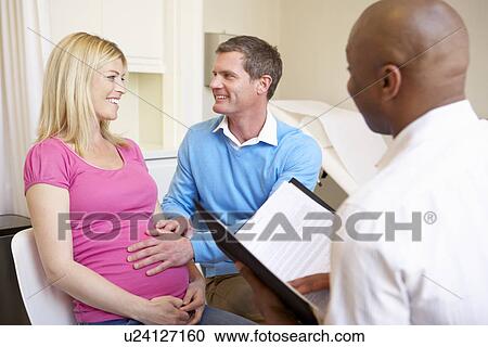Stock Image - Couple Meeting With Obstetrician In Clinic. Fotosearch