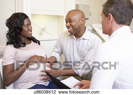 Stock Image - Couple Meeting With Obstetrician In Clinic. Fotosearch