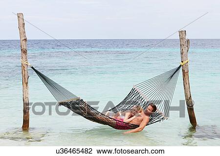 Stock Image - Couple Relaxing In Beach Hammock . Fotosearch