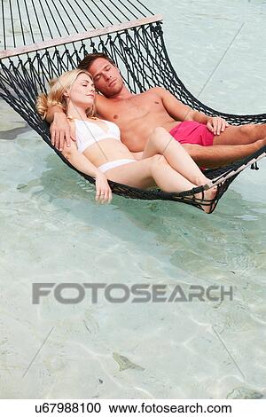 Stock Image - Couple Relaxing In Beach Hammock . Fotosearch