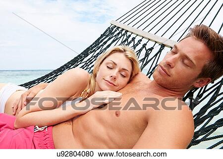 Stock Image - Couple Relaxing In Beach Hammock . Fotosearch