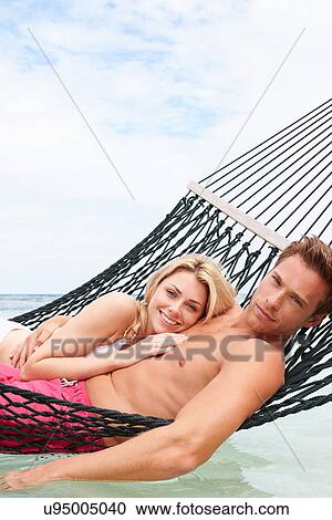 Stock Image - Couple Relaxing In Beach Hammock . Fotosearch